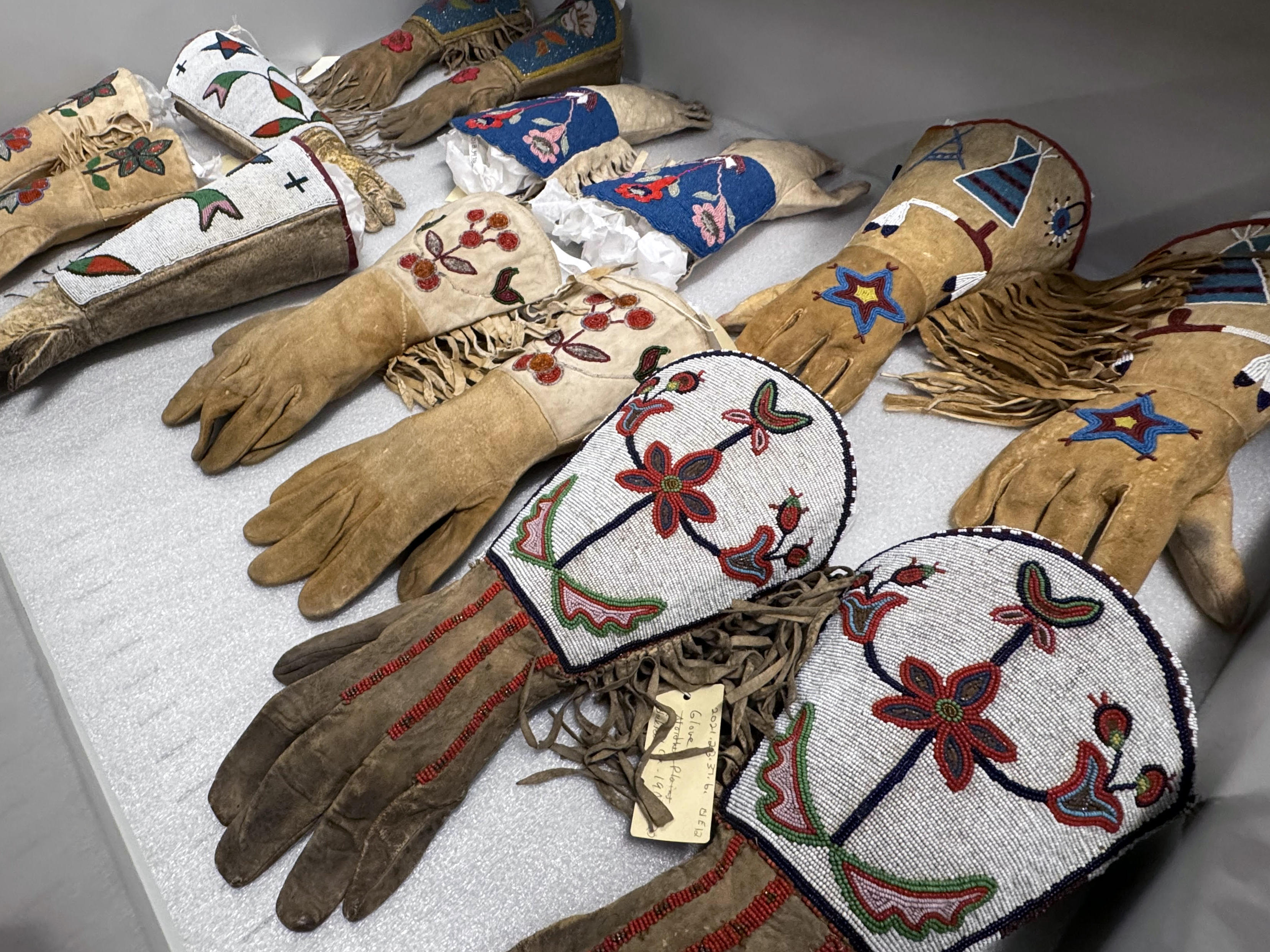 Image showing a drawer in MTHS Collections that is full of colorful beaded indigenous gloves 