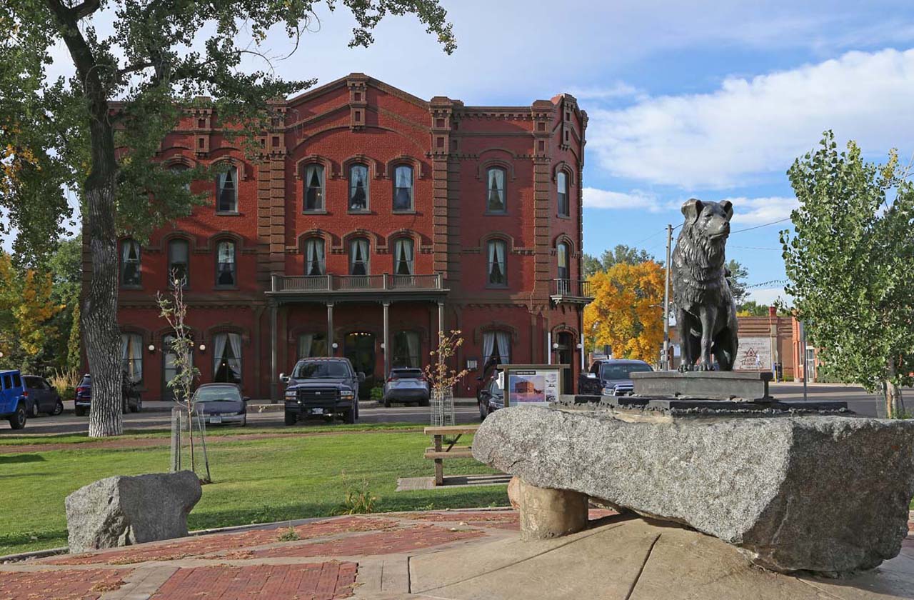 Photograph of the 'Shep' statue in the foreground with the Grand Union Hotel in the background in Fort Benton, Montana
